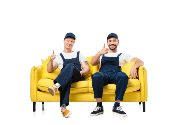 שני מובילים באוברול כחול על ספה צהובה מסמנים אגודל למעלה