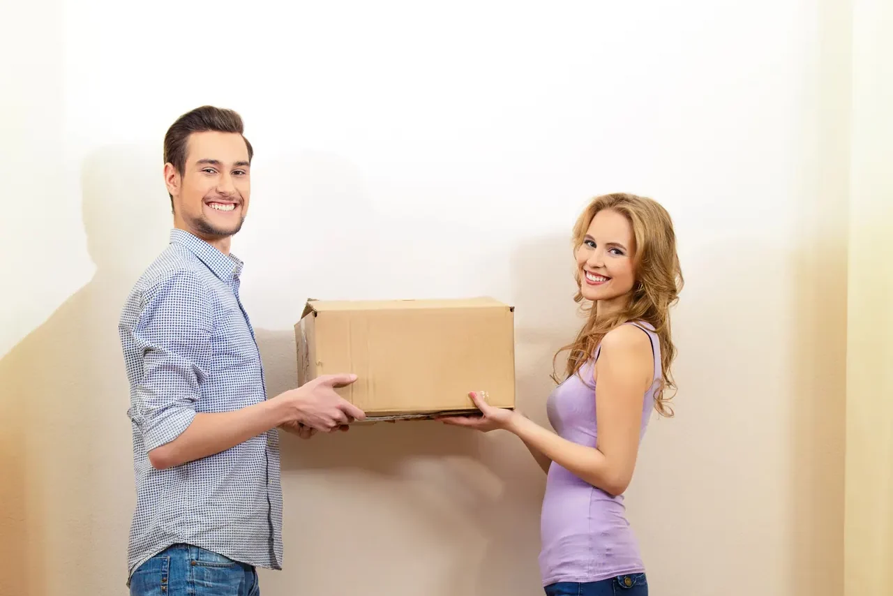 גבר ואישה נושאים יחד ארגז קרטון בדירה כמעט ריקה