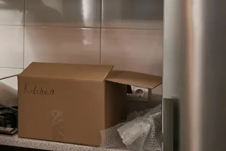 ארגז קרטון מסומן בכתב יד וניילון בועות על משטח, ליד דופן נירוסטה