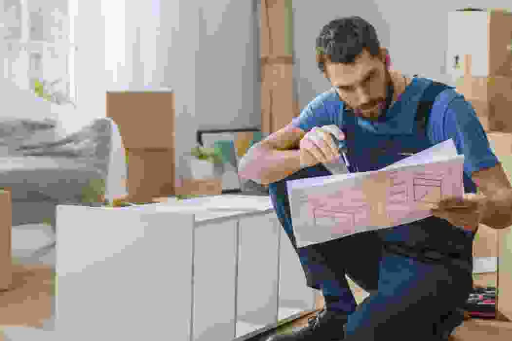 גבר מחזיק דף תכנית במטבח חדש עם ארגזי קרטון ברקע