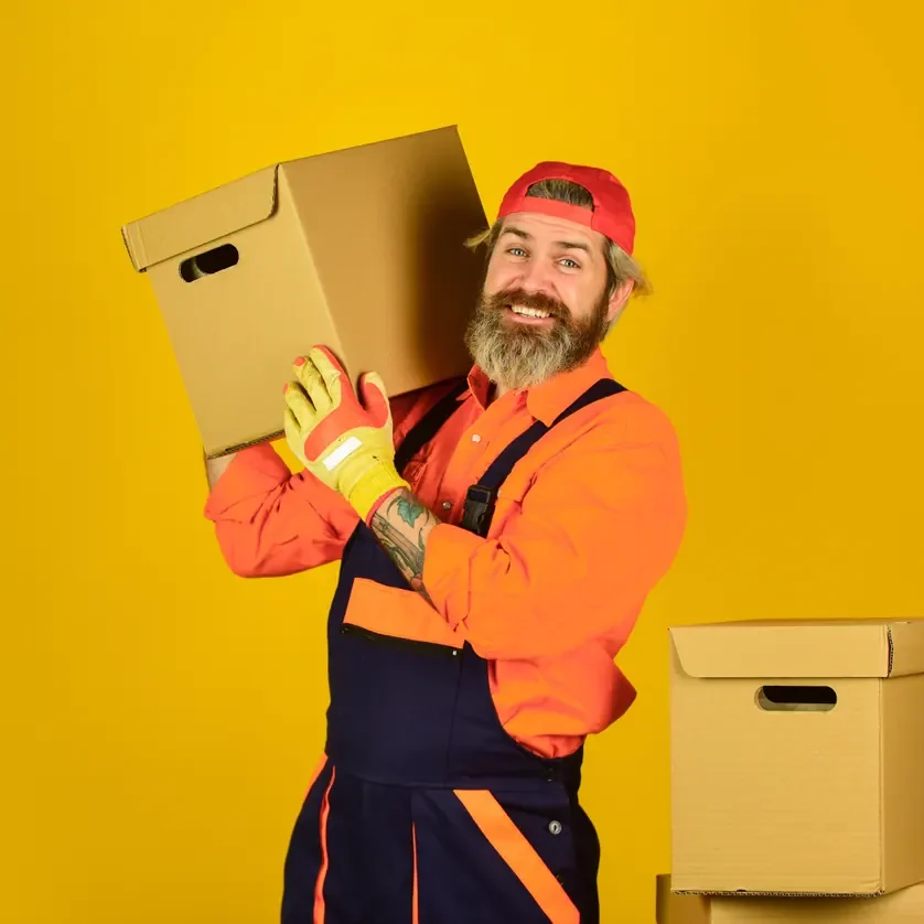 מוביל בסרבל כתום נושא ארגז על הכתף על רקע צהוב