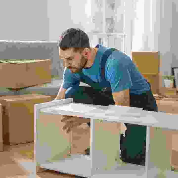 עובד מרכיב גוף ארון מטבח לבן על רצפת החדר