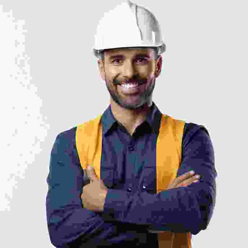 עובד באפוד זוהר וקסדה לבנה עומד עם ידיים משולבות על רקע בהיר