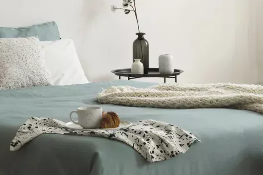 מיטה מוצעת עם מגש קפה ונרות על שמיכה בשעת בוקר מוקדמת