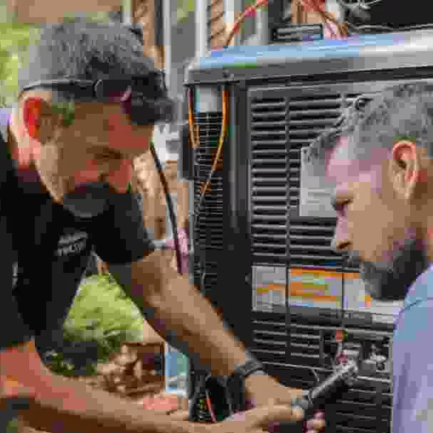שני טכנאים עובדים יחד על יחידה חיצונית עם כלי עבודה