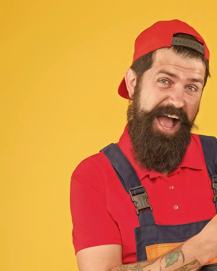 עובד מחייך עם כובע אדום וסרבל עבודה על רקע צהוב